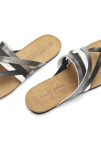 Sandales à lanières avec une semelle en liège. Comprend des bandes métalliques argentées, noires et blanches avec une semelle plate. Logo de la marque embossé sur la semelle intérieure.
