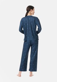 Mörkblå pyjamas-set med långärmad topp och vida byxor. Har små, ljusblå stjärnmönster överallt. Mjuk tygfinish.
