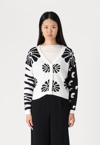 Cardigan tricoté noir et blanc avec des motifs floraux et abstraits, décolleté en V, fermeture à boutons et poignets côtelés. Design mi-court.