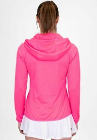 Felroze hoodie met lange mouwen, gemaakt van een zachte stof en met een aansluitende pasvorm, gecombineerd met een witte uitlopende rok aan de zoom.