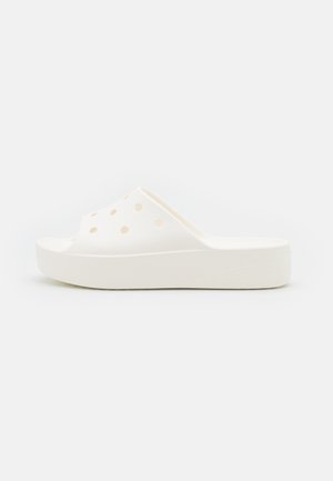 Hvide slip-on sandaler med perforeret overdel, tekstureret sål og platformsbund, lavet af letvægtsmateriale.