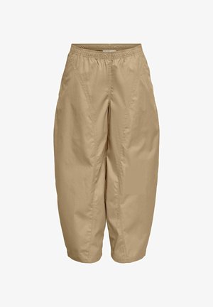 Pantalon beige court avec taille élastique et poches latérales, présentant des coutures visibles à l’avant et une coupe ample à jambes larges.