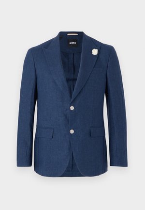 Marineblauer Leinenblazer mit Reverskragen, zwei Fronttaschen, drei Knöpfen und einer dekorativen weißen Blumenstecknadel am linken Revers.