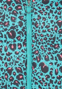 Tyrkysová bunda typu puffer s černě růžovým leopardím potiskem, se zapínáním na přední zip s táhlem ve tvaru srdce. Hladká textura.