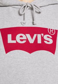 Felpa grigia in cotone con logo rosso Levi's. Presenta un cappuccio con cordoncino e una finitura testurizzata, che mette in mostra il design distintivo del marchio.