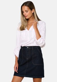 Lightweight, pink and white striped blouse with a v-neck, paired with a dark denim A-line skirt featuring front pockets and contrast stitching.