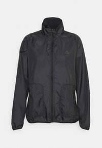 Chaqueta cortaviento negra hecha de tela ligera y texturizada con cuello alto, cierre de cremallera y dos bolsillos laterales. Presenta un logo sutil.