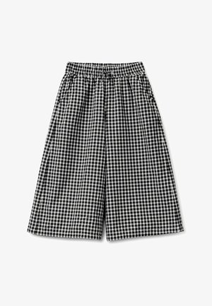 Shorts à larges jambes à carreaux noir et blanc avec ceinture élastique et poches latérales, posés à plat sur un fond blanc.