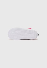 Semelle de sneaker blanche avec un motif de grip texturé, comportant un accent rose au niveau du talon et un petit logo près de l'arrière.