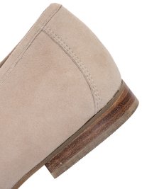 Beige mokkasko med hæl, synlige syninger og en stakket træsål med teksturerede kanter.