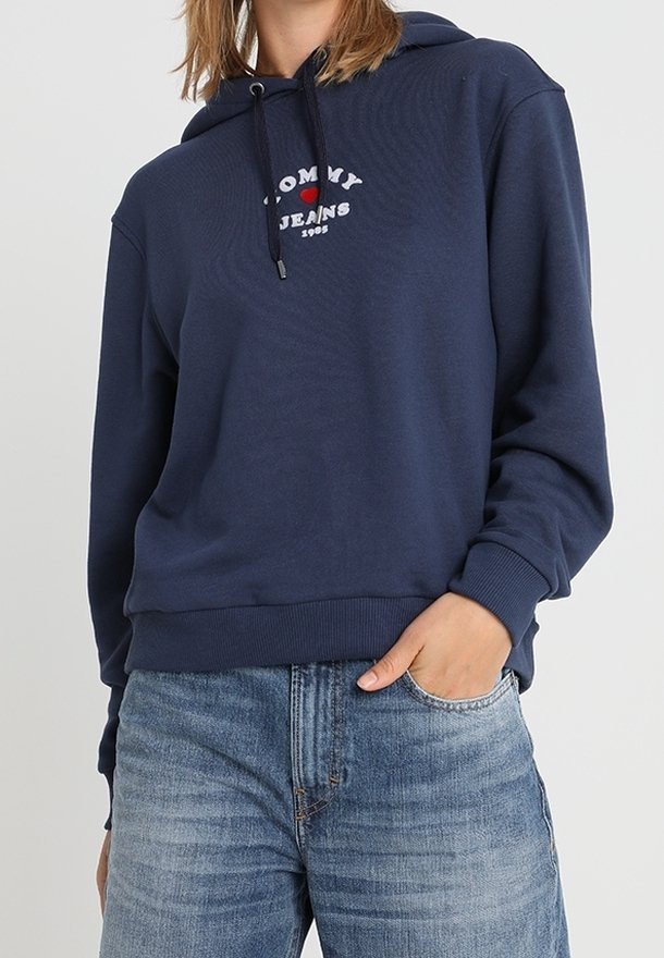 Navy blue hoodie made of soft fabric, featuring a front graphic with "TOMMY JEANS" and a heart emblem. Elastic cuffs and waistband.