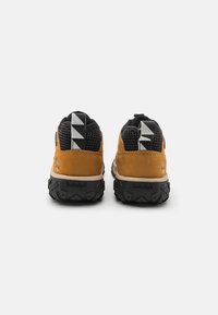 Barna velúr és fekete hálós sportcipő, textúrált fekete gumitalppal, háromszögletű mintázatú sarokhúzóval és Timberland logóval.