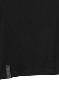 Black cotton t-shirt featuring a textured finish, a straight hem, and a small branded label on the left side of the bottom hem.