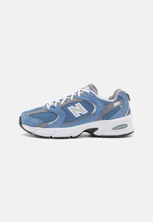 Blauwe suède en mesh sneakers met witte veters, grijze accenten en een gevoerde witte zool. Heeft een opvallend "N"-logo aan de zijkant.