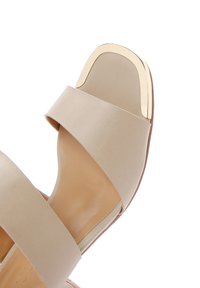 Sandal in pelle beige con due fasce larghe e un accento metallico dorato nella zona delle dita. Texture liscia e forma sagomata.