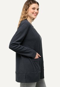 Mörkgrå lång cardigan av texturerat stickat material, med avslappnad passform, sidofickor och en delad fålldesign.