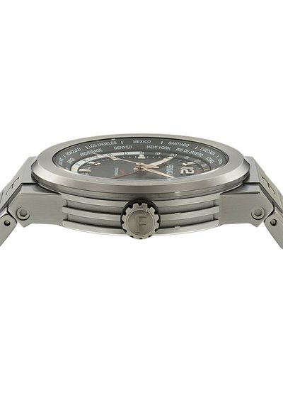 Reloj de acero inoxidable con una esfera negra, con nombres de ciudades alrededor del bisel, manecillas plateadas y una corona prominente con el logotipo "F".