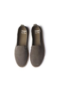 Olīvzaļa espadrilles ar perforētu zābaku augšdaļu, elastīgām sānu paneļiem un dabīgo jutu zoli. Zīmola nosaukums "TONI" redzams iekšpusē.