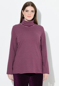 Top de cuello alto a rayas moradas y blancas con mangas largas, que presenta una textura suave y un corte relajado, combinado con pantalones de pana morados.