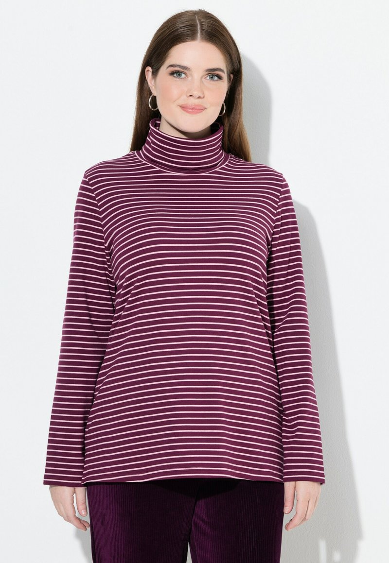 Top de cuello alto a rayas moradas y blancas con mangas largas, que presenta una textura suave y un corte relajado, combinado con pantalones de pana morados.