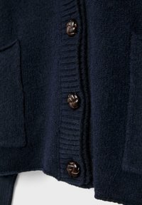 Marineblauer Cardigan aus strukturierter Wolle, mit geripptem Saum, zwei Fronttaschen und großen, gewebten braunen Knöpfen.