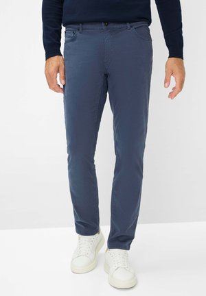 Marineblaue Chinos aus Baumwollmischung mit Seitentaschen, slim fit und glatter Textur. Kombiniert mit weißen Sneakers.