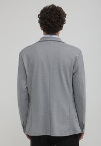 Grau blazer aus glattem Material, mit Reverskragen und Dreiknopf-Detail. Verfügt über zwei seitliche Taschen und eine taillierte Passform mit geschlitzenem Rücken.