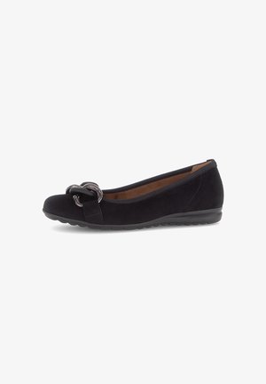 Zwarte suède platte schoen met lage hak en decoratieve zwarte kettingdetails op de teen, met een ronde neus en een slip-on ontwerp.