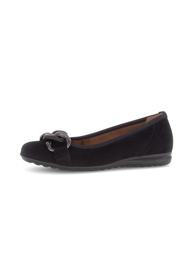 Zwarte suède platte schoen met lage hak en decoratieve zwarte kettingdetails op de teen, met een ronde neus en een slip-on ontwerp.