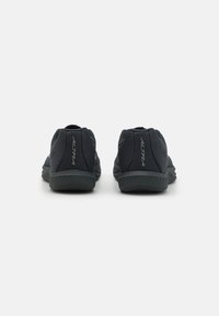 Baskets de sport noires avec une tige texturée et une semelle rembourrée. Présente un ajustement serré et un design minimaliste. Logo sur le talon.