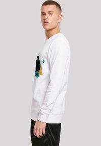 Hvit langermet sweatshirt med en fargerik grafisk trykk som viser en svart katt og sirkulære detaljer. Ribbet mansjetter og kant.