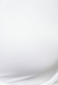 Soutien-gorge blanc en tissu lisse et extensible, doté d'un design rembourré et de bords sans couture pour une apparence épurée.