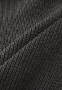 Dark gray, ribbed fabric showing a textured, knitted pattern with diagonal lines. Soft material with visible fibers and a slightly fuzzy surface.