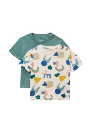 Deux t-shirts pour tout-petits, l'un vert uni et l'autre blanc avec des formes abstraites colorées, tous deux avec des boutons sur l'épaule.