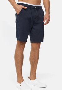 Mørkeblå shorts lavet af blødt stof, med knaplukning, snoretræk i taljen, sidelommer og opkrøllede kanter for et afslappet look.