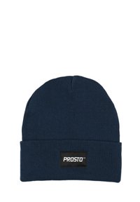 Granatowa prążkowana dziana czapka z wywiniętym mankietem i prostokątną czarną metką z białym napisem. Miękki, elastyczny materiał.