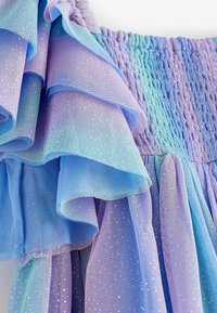 Kerroksittain oleva tüllimekko sinisen ja violetin liukuvärjätyissä sävyissä. Mekossa on röyhelöreunat, hohtavat yksityiskohdat ja smokkauksella viimeistelty yläosa.