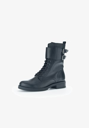 Schwarze Leder-Stiefelette mit Schnürung, gepolstertem Knöchelriemen und zwei silbernen Schnallendetails. Flache Sohle und abgerundete Zehenform.