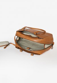 Bruine leren tas met een ritssluiting, twee handvatten bovenaan en een lichtgrijze binnenkant. Beschikt over een buitenvak en organiserende compartimenten aan de binnenzijde.