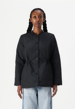 Black quilted jacket with a button front, drawstring waist, and long sleeves. Features a rounded collar and a textured wave pattern.