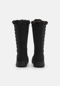 Botas negras de caña alta con un diseño acolchado, forro de piel sintética en el dobladillo y un acabado suave y mate con suela de goma.