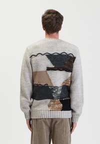 Maglione lavorato a maglia con un motivo geometrico multicolore sulla parte posteriore, principalmente in tonalità di grigio, marrone e nero, con un orlo a coste.