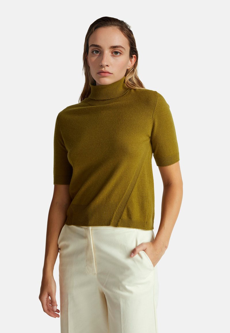 Svetr s krátkým rukávem a rolákem v olivově zelené barvě, vyrobený z měkkého materiálu s žebrovanými detaily, zdobený diagonálním švem a volným střihem.