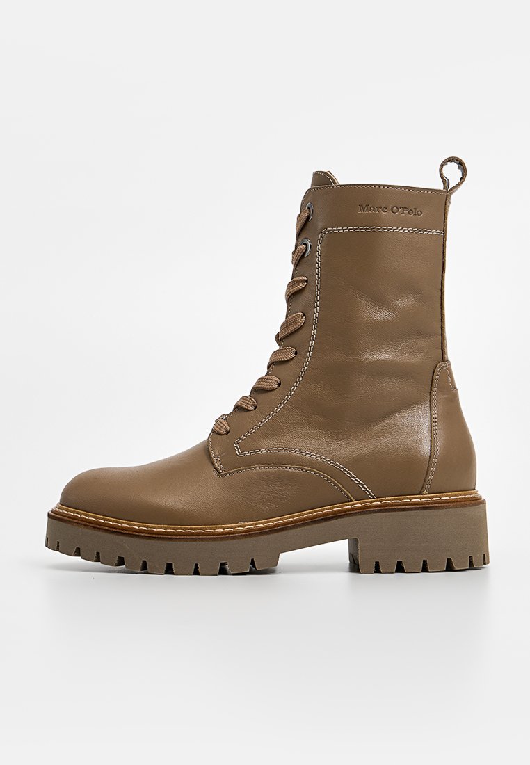 Bottes chelsea en cuir marron avec un laçage sur le devant, un col rembourré et une semelle texturée. Présente des détails cousus et une tirée à l'arrière.