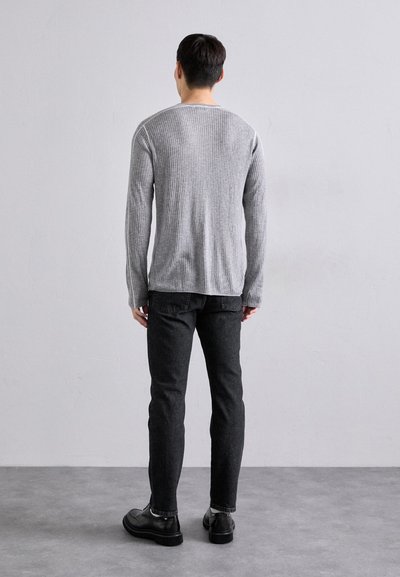 Grå stripete strikkegenser, rund halslinning, lange ermer; sammen med mørkegrå slim-fit jeans og svarte lær-sko. Enkelt og strukturert design.