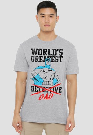 Young man wearing a gray T-shirt with a blue Batman graphic and text "WORLD'S GREATEST ~DETECTIVE~ DAD" in bold black and red letters.