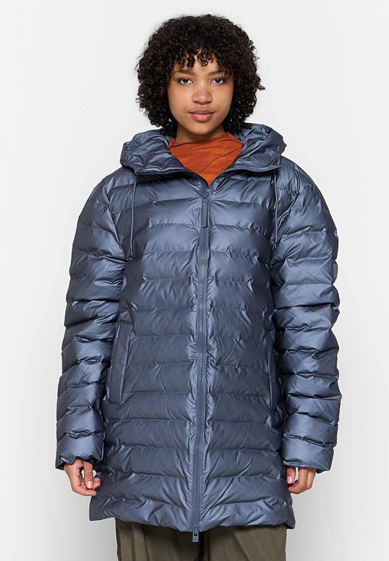Veste d'extérieur rembourrée de couleur bleu métallisé. Elle possède une capuche, une fermeture éclair à l'avant et des coutures horizontales pour l'isolation. Texture lisse et brillante.