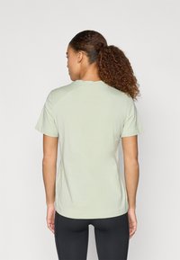 Svijetlozeleni pamukasti majica s kružnim izrezom i kratkim rukavima. Pogled s leđa prikazuje standardni kroj i glatku teksturu bez uzoraka.