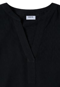 Czarna bluzka z subtelnym wzorem teksturalnym, dekoltem w serek i krótkimi rękawami. Metka wewnątrz dekoltu głosi "CECIL".