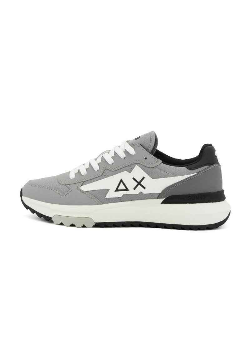 Scarpa sportiva grigia con una combinazione di materiali lisci e testurizzati, dettagli bianchi, un logo geometrico e un tacco nero. Suola in gomma.